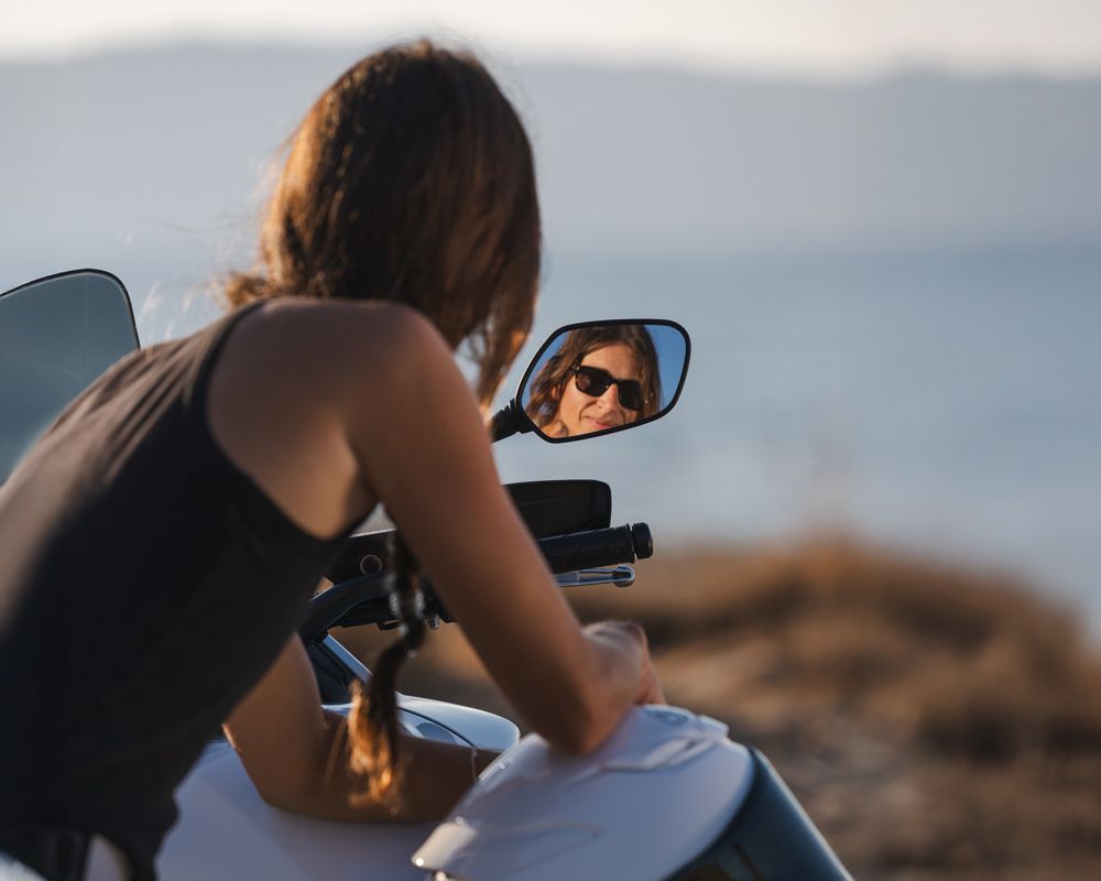 Καλλι χαμογελάει στο καθρέφτη της Honda NX 500 φορώντας γυαλιά ηλίου – GAS Rider Stories #3